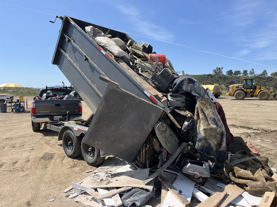 Our dump trailer raised and tipping a full household load onto the working face of a Los Angeles County transfer station, a wheel loader waiting in the background