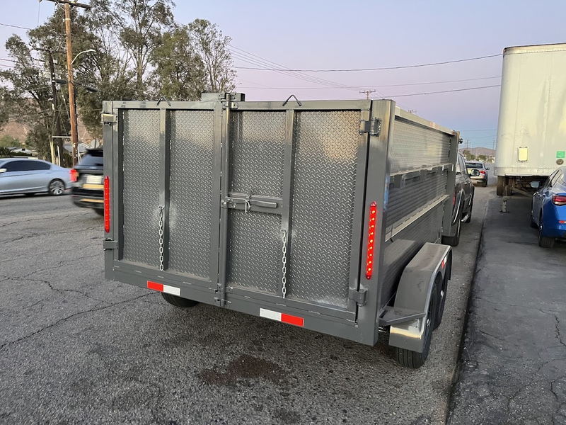 Our gray steel dump trailer with diamond-plate tailgate parked curbside on a Los Angeles County street, empty and ready for the next load