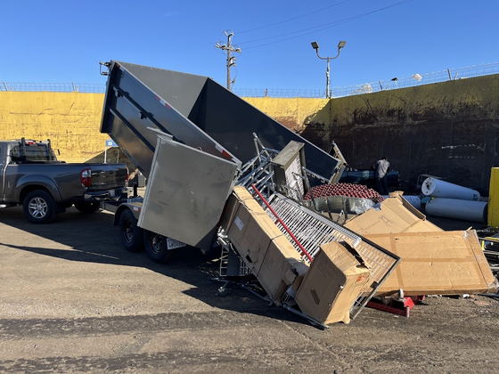 Our dump trailer raised and tipping a commercial load of flat-pack cartons and steel shelving out onto the floor of a Los Angeles County recycling yard